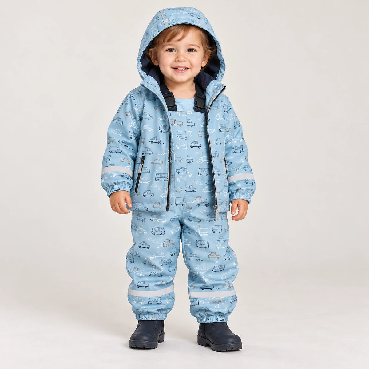 Toddler wearing HONEYKING fleece-lined rain jacket and bib rain pants in light blue car print with rain boots